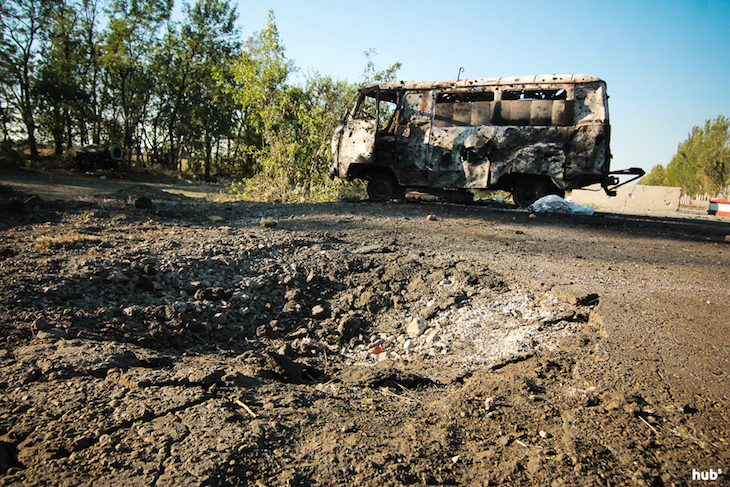 След от снаряда и сгоревший микроавтобус на блок-посту территориальной обороны возле пункта пропуска "Новоазовск"